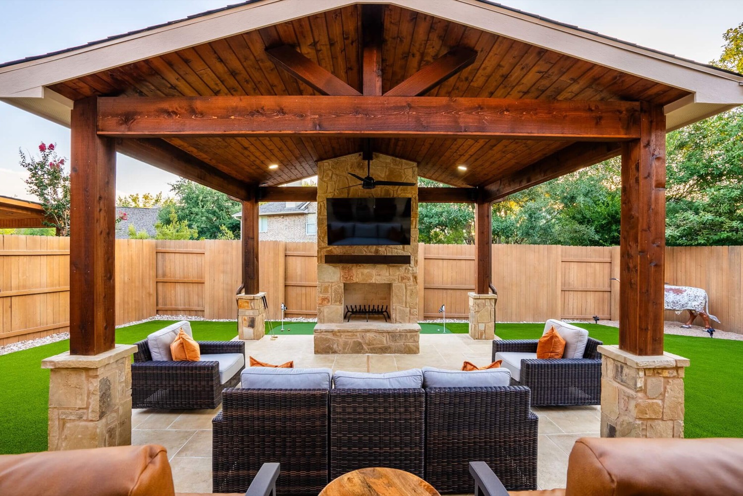 Covered outdoor living area with stone fireplace and vaulted wood ceiling